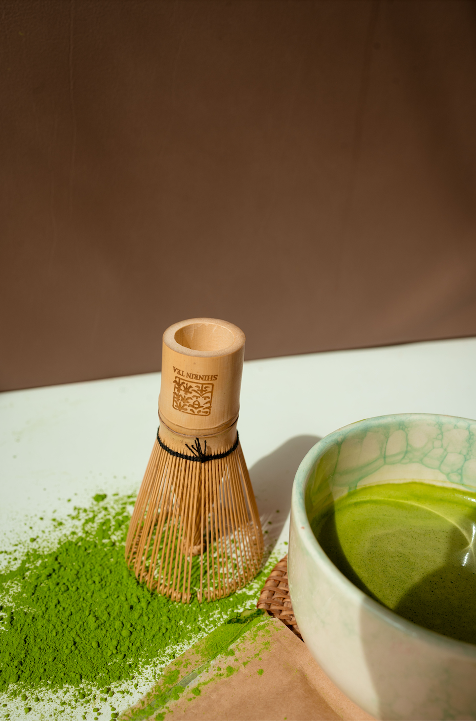 Product_Picture_Shinrin_Tea_Matcha_on_the_Surface_with_the_Shinrin_Tea_Whisk_with_Logo_and_a_cup_of_Matcha